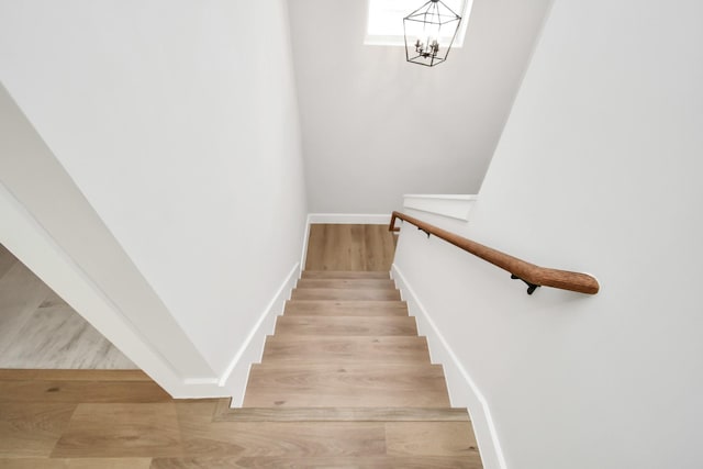 stairway featuring wood-type flooring and a notable chandelier