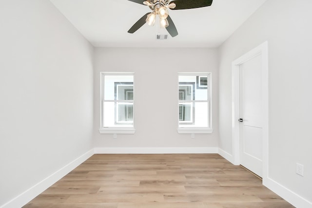 empty room with ceiling fan, a wealth of natural light, and light hardwood / wood-style flooring