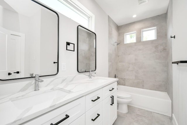 full bathroom featuring tile patterned floors, tiled shower / bath combo, vanity, and toilet