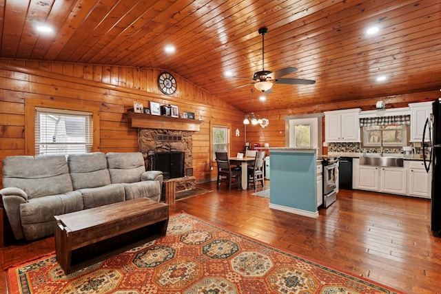 living room featuring lofted ceiling, a stone fireplace, sink, dark hardwood / wood-style floors, and ceiling fan