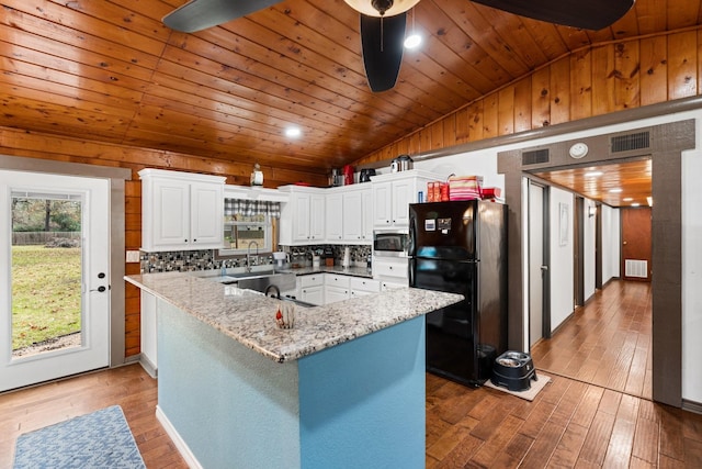 kitchen featuring black refrigerator, wood-type flooring, white cabinetry, tasteful backsplash, and vaulted ceiling