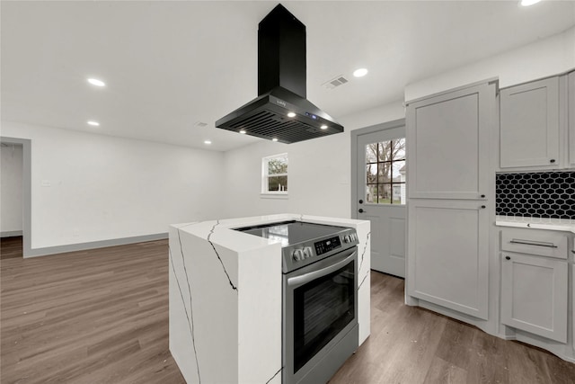 kitchen with light hardwood / wood-style floors, a center island, island range hood, and stainless steel electric range