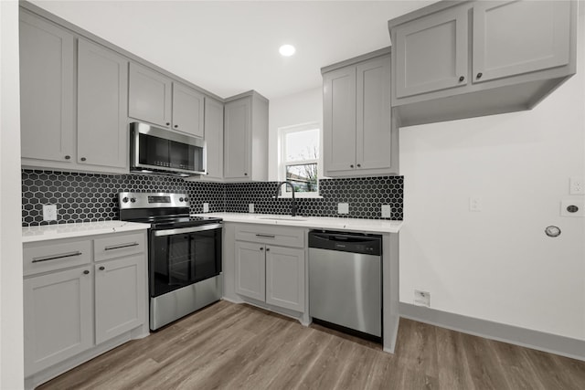 kitchen featuring light wood-type flooring, sink, gray cabinetry, and stainless steel appliances