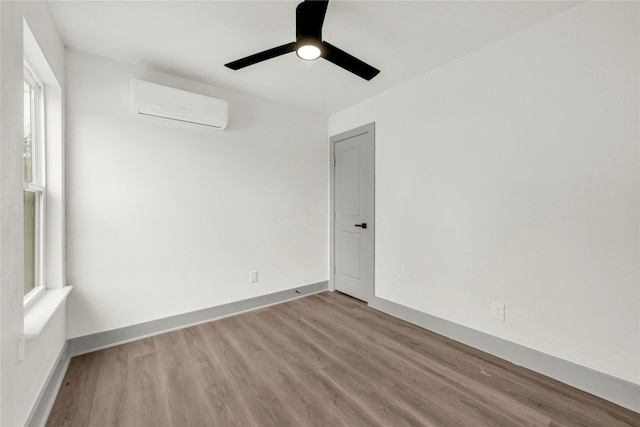 empty room with ceiling fan, a wall mounted AC, and light wood-type flooring