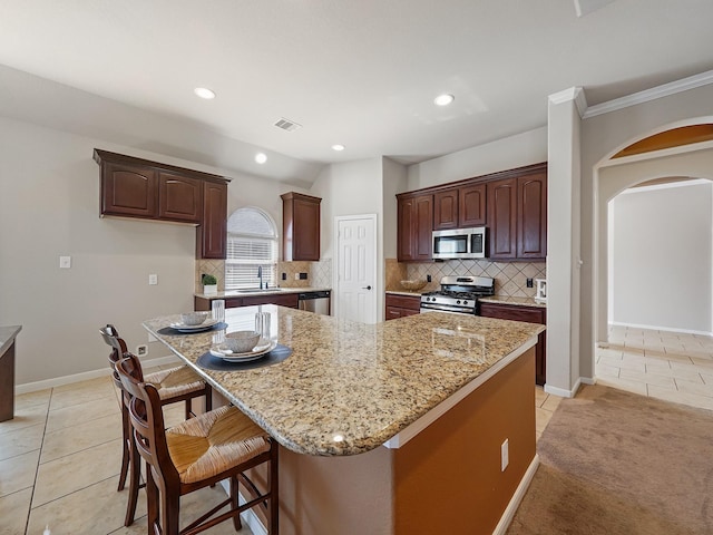 kitchen featuring light stone counters, a breakfast bar area, stainless steel appliances, and a kitchen island