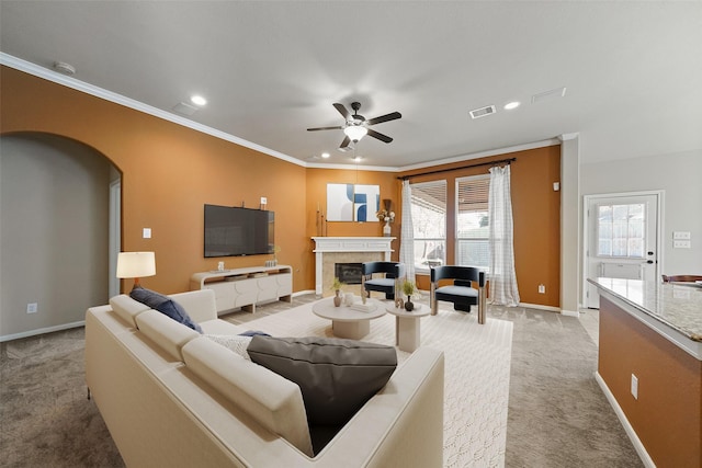 living room with ceiling fan, ornamental molding, light colored carpet, and a fireplace