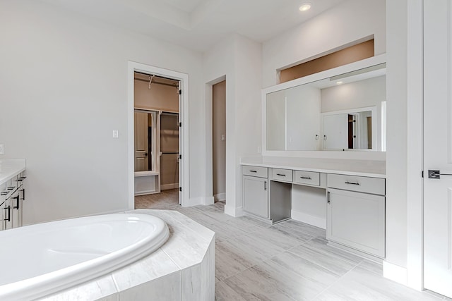 bathroom with tiled tub and vanity