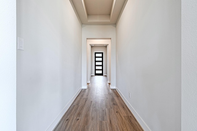 corridor featuring light hardwood / wood-style floors and a raised ceiling