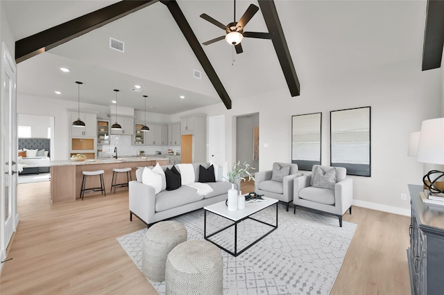 living room featuring sink, high vaulted ceiling, light hardwood / wood-style flooring, ceiling fan, and beam ceiling