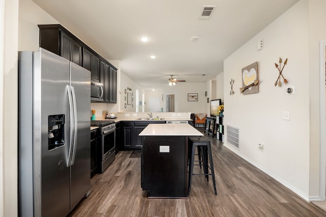 kitchen featuring ceiling fan, a center island, a breakfast bar, sink, and appliances with stainless steel finishes