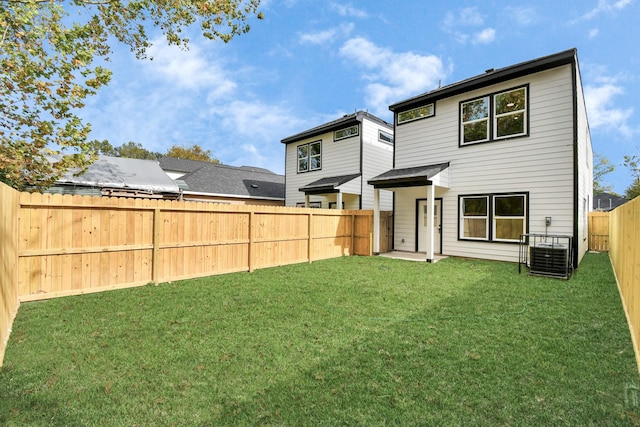 rear view of property with central air condition unit and a lawn