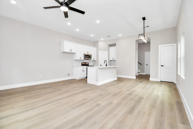 unfurnished living room with ceiling fan, sink, and light hardwood / wood-style floors