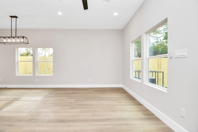 unfurnished room with a notable chandelier and light hardwood / wood-style flooring