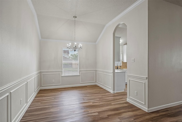 unfurnished dining area featuring a notable chandelier, wood-type flooring, a textured ceiling, crown molding, and sink