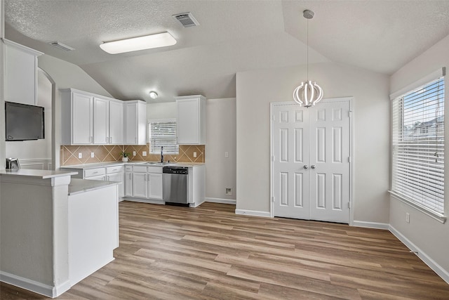 kitchen with lofted ceiling, white cabinetry, decorative backsplash, and dishwasher