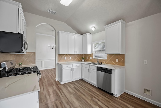 kitchen with white cabinetry, appliances with stainless steel finishes, lofted ceiling, light stone counters, and sink