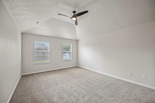 carpeted empty room featuring a textured ceiling, ceiling fan, and vaulted ceiling