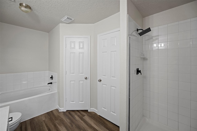 bathroom with a textured ceiling, toilet, wood-type flooring, and plus walk in shower