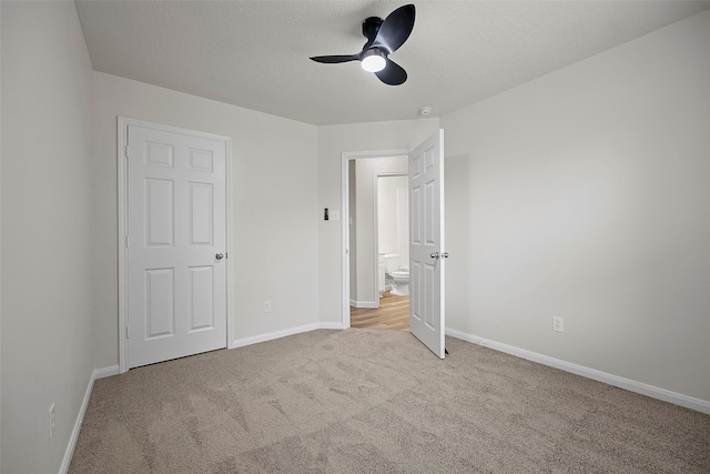 unfurnished bedroom featuring ceiling fan, light colored carpet, and a textured ceiling