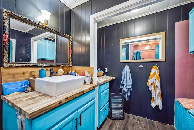 bathroom with hardwood / wood-style flooring, vanity, crown molding, and wood walls