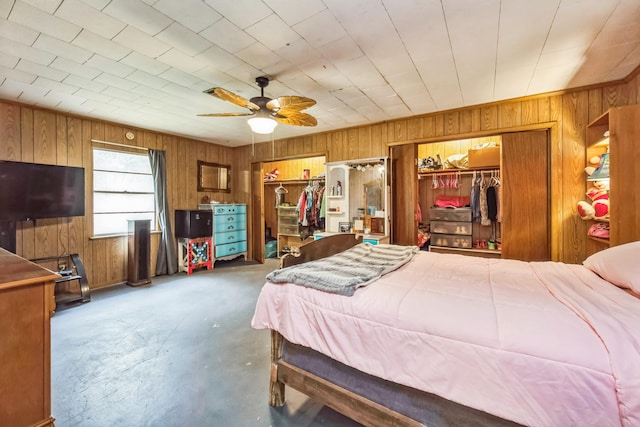 bedroom with concrete flooring, wooden walls, and ceiling fan