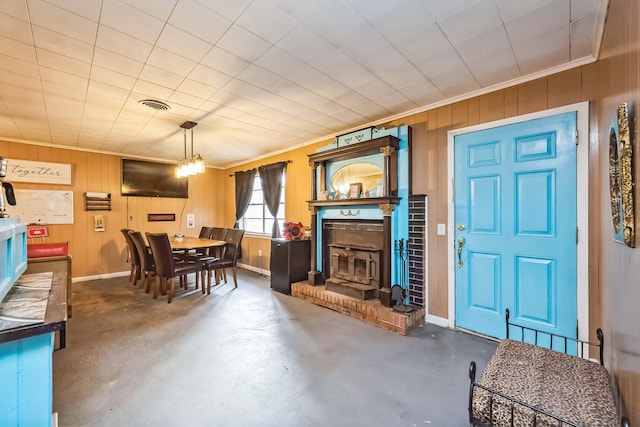 living room with crown molding, wooden walls, and a wood stove