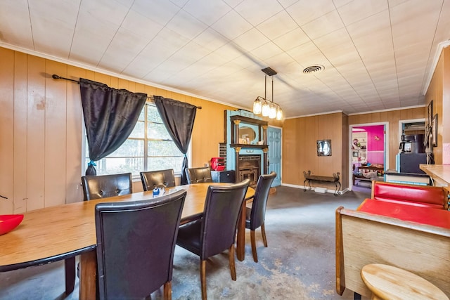 dining room with ornamental molding, a chandelier, dark carpet, and wood walls