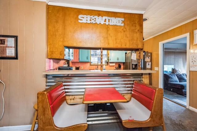 bar with crown molding, stainless steel fridge, and wood walls