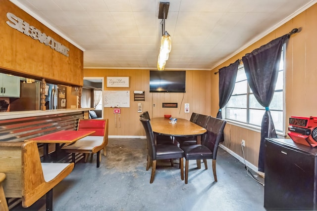 dining room with ornamental molding and wooden walls