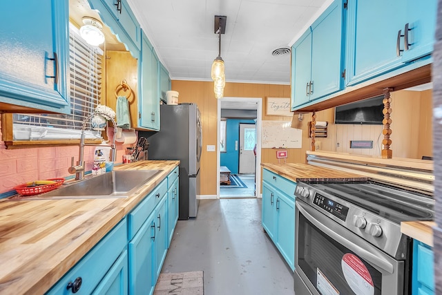 kitchen with blue cabinetry, appliances with stainless steel finishes, butcher block counters, and pendant lighting