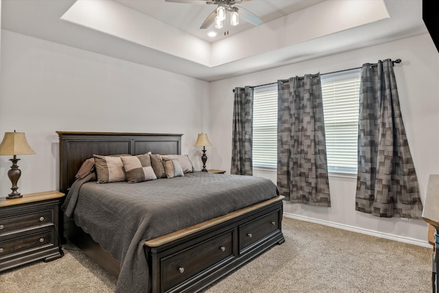 carpeted bedroom with ceiling fan and a tray ceiling