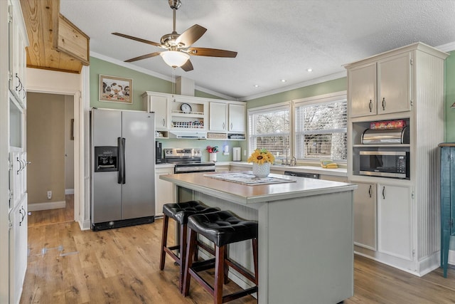 kitchen featuring stainless steel appliances, vaulted ceiling, a kitchen breakfast bar, a textured ceiling, and a center island