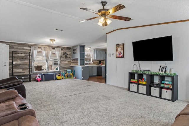 living room featuring a textured ceiling, wooden walls, ceiling fan, dark carpet, and crown molding