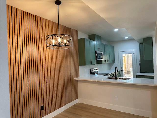 kitchen featuring an inviting chandelier, green cabinets, appliances with stainless steel finishes, hanging light fixtures, and sink