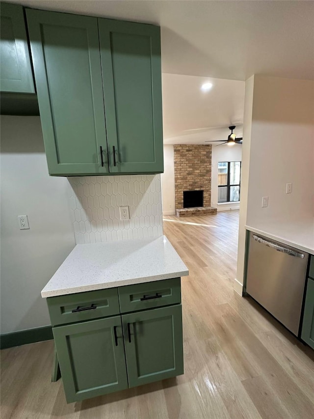 kitchen with green cabinets, stainless steel dishwasher, and light stone counters