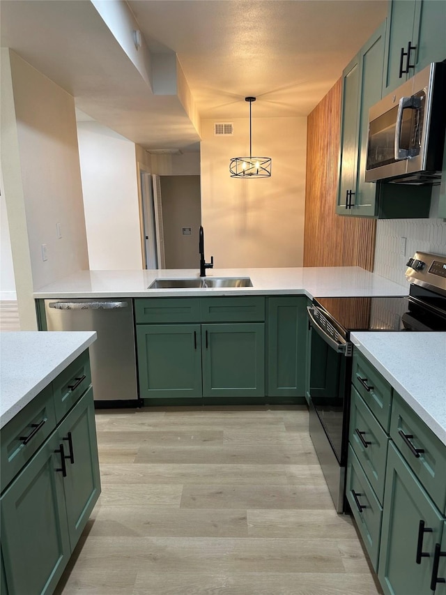 kitchen featuring sink, pendant lighting, stainless steel appliances, and green cabinetry