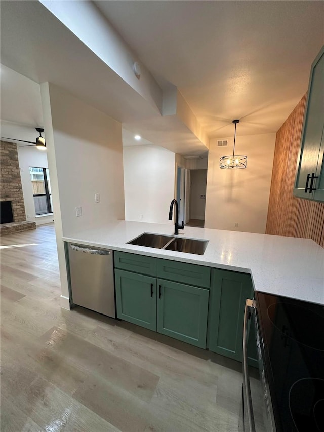 kitchen featuring pendant lighting, dishwasher, a stone fireplace, sink, and green cabinets