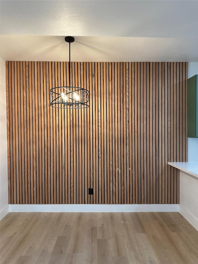 unfurnished dining area featuring a chandelier and light wood-type flooring