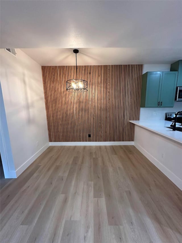 unfurnished dining area featuring sink, an inviting chandelier, and light wood-type flooring