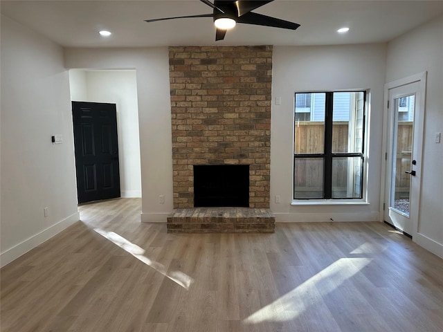 unfurnished living room featuring ceiling fan, light hardwood / wood-style flooring, and a brick fireplace