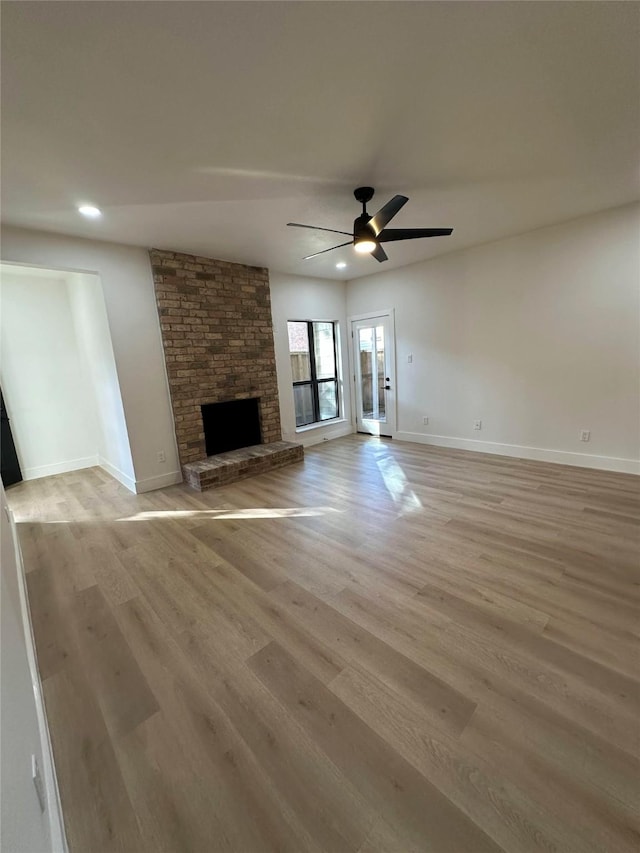 unfurnished living room featuring ceiling fan, light hardwood / wood-style floors, and a fireplace