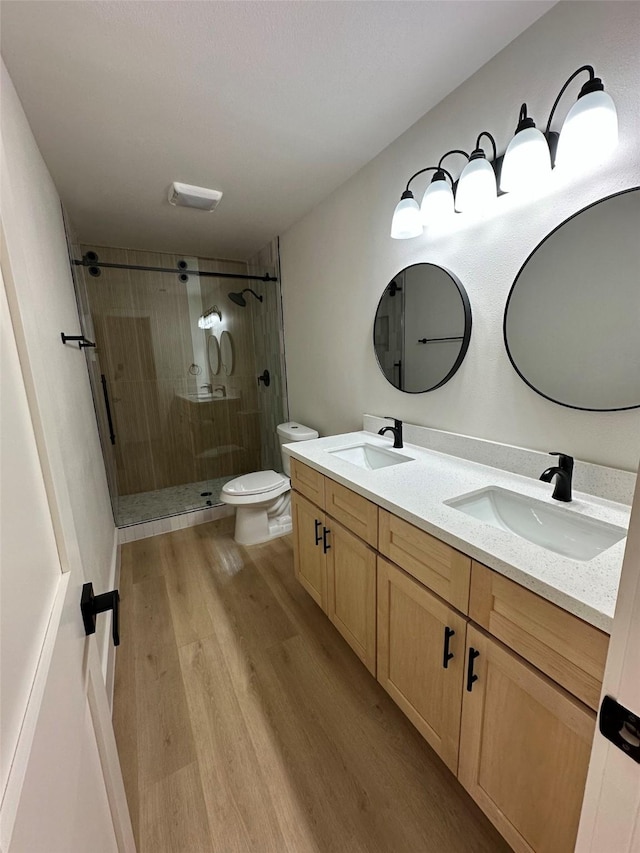 bathroom featuring toilet, vanity, a shower with door, and hardwood / wood-style flooring