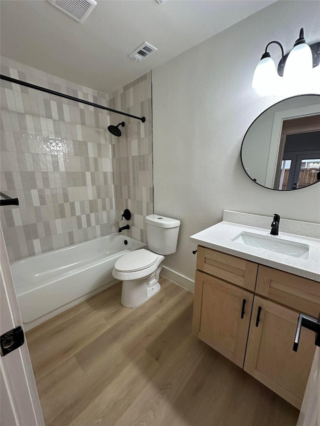 full bathroom featuring hardwood / wood-style floors, toilet, vanity, and tiled shower / bath combo