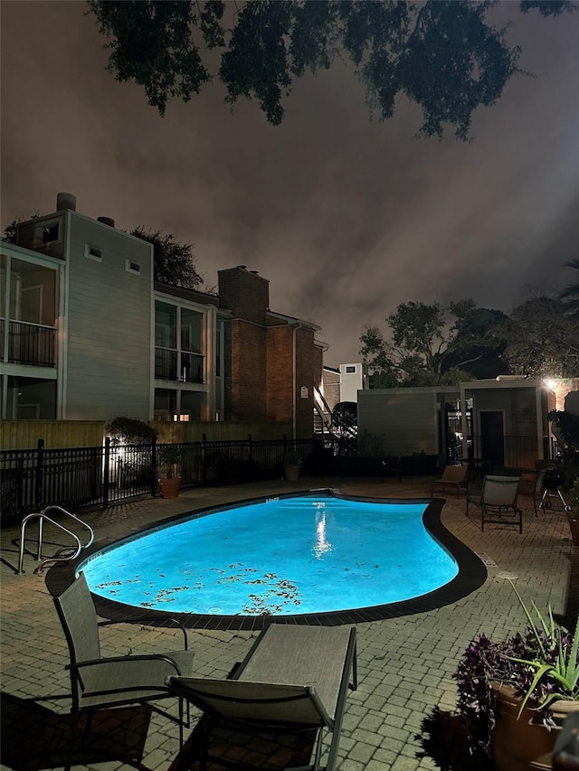 pool at dusk with a patio area