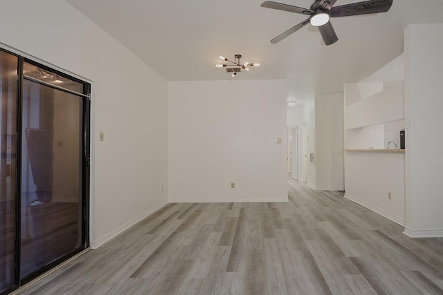 unfurnished room with ceiling fan with notable chandelier and light hardwood / wood-style flooring