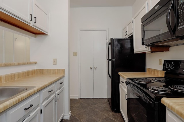 kitchen featuring sink, white cabinetry, dark tile patterned floors, and black appliances