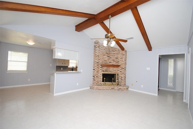 unfurnished living room with a brick fireplace, ceiling fan, high vaulted ceiling, and beamed ceiling