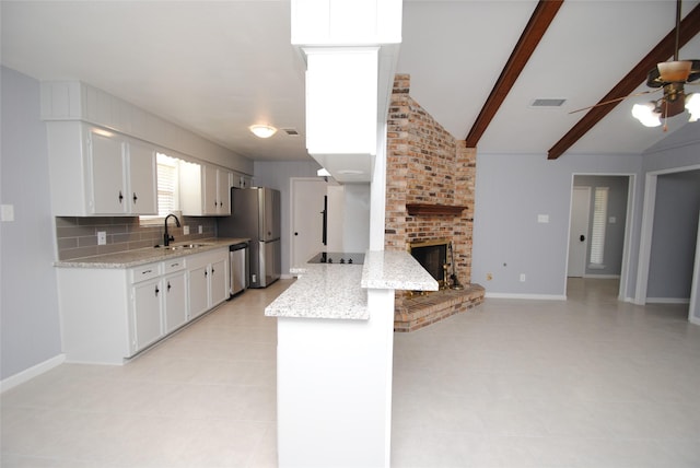 kitchen with light stone counters, white cabinets, lofted ceiling with beams, and a fireplace