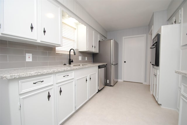 kitchen with black oven, white cabinetry, tasteful backsplash, sink, and stainless steel dishwasher