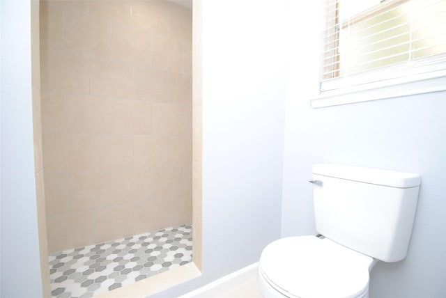 bathroom with toilet and a tile shower